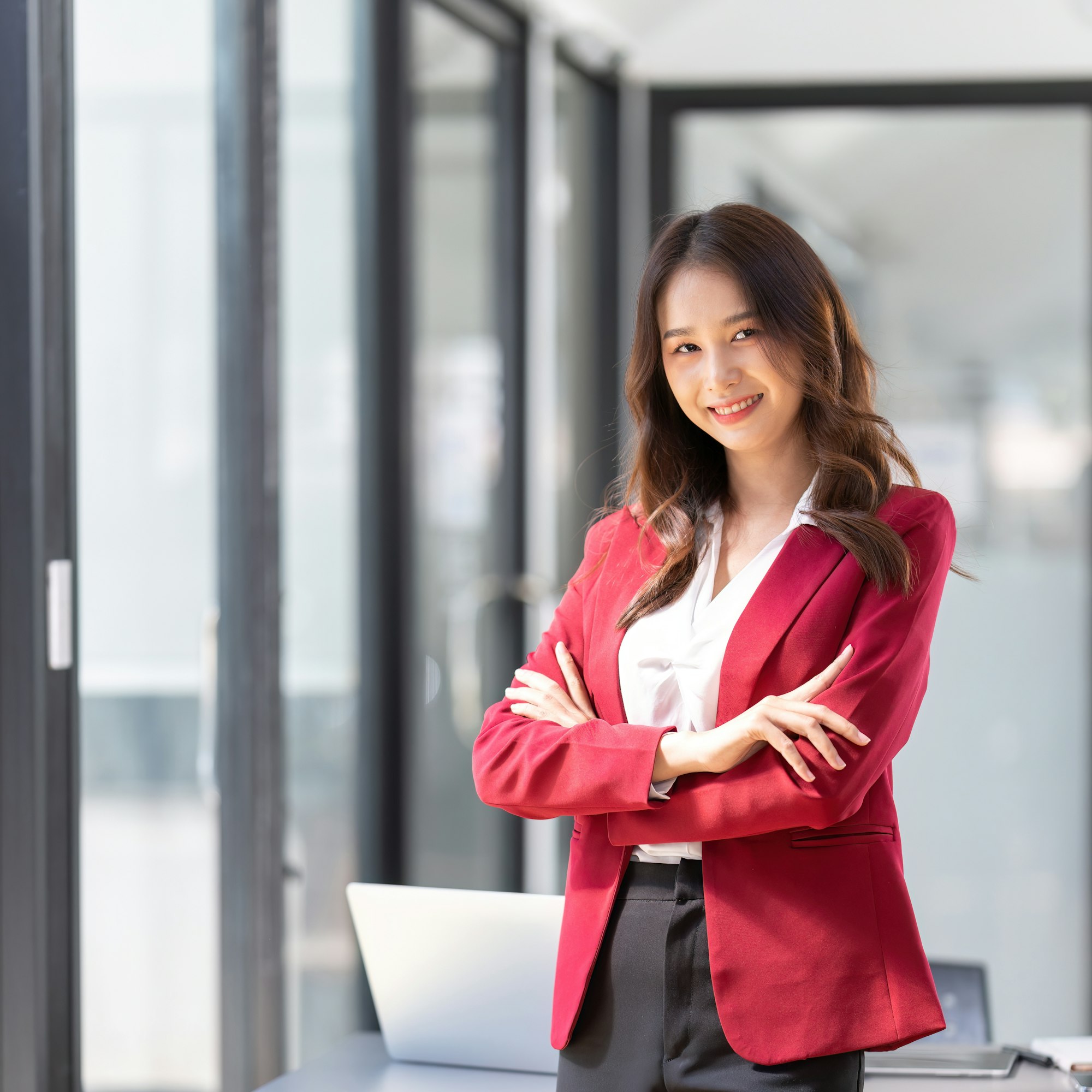 Businesswoman entrepreneur or an office worker stands with crossed arms near a desk in a office